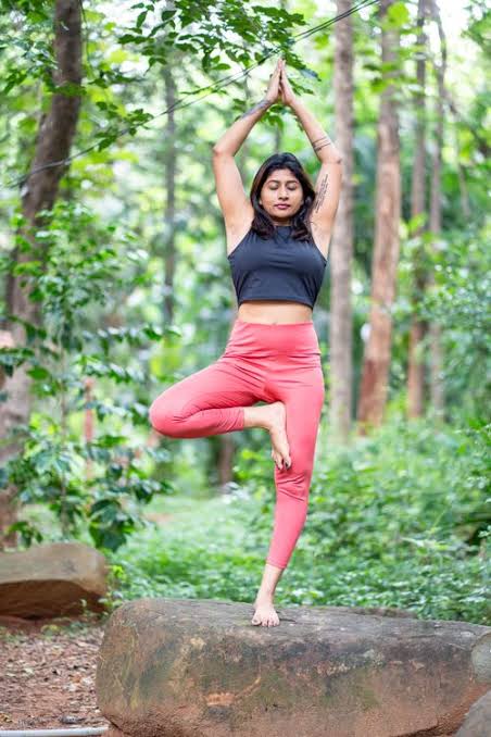 Woman practicing the yoga tree pose in a forest